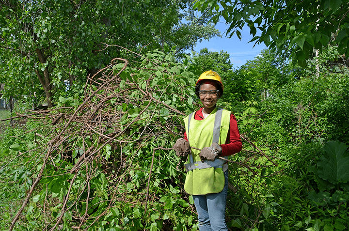 member smiling in front of brush pile