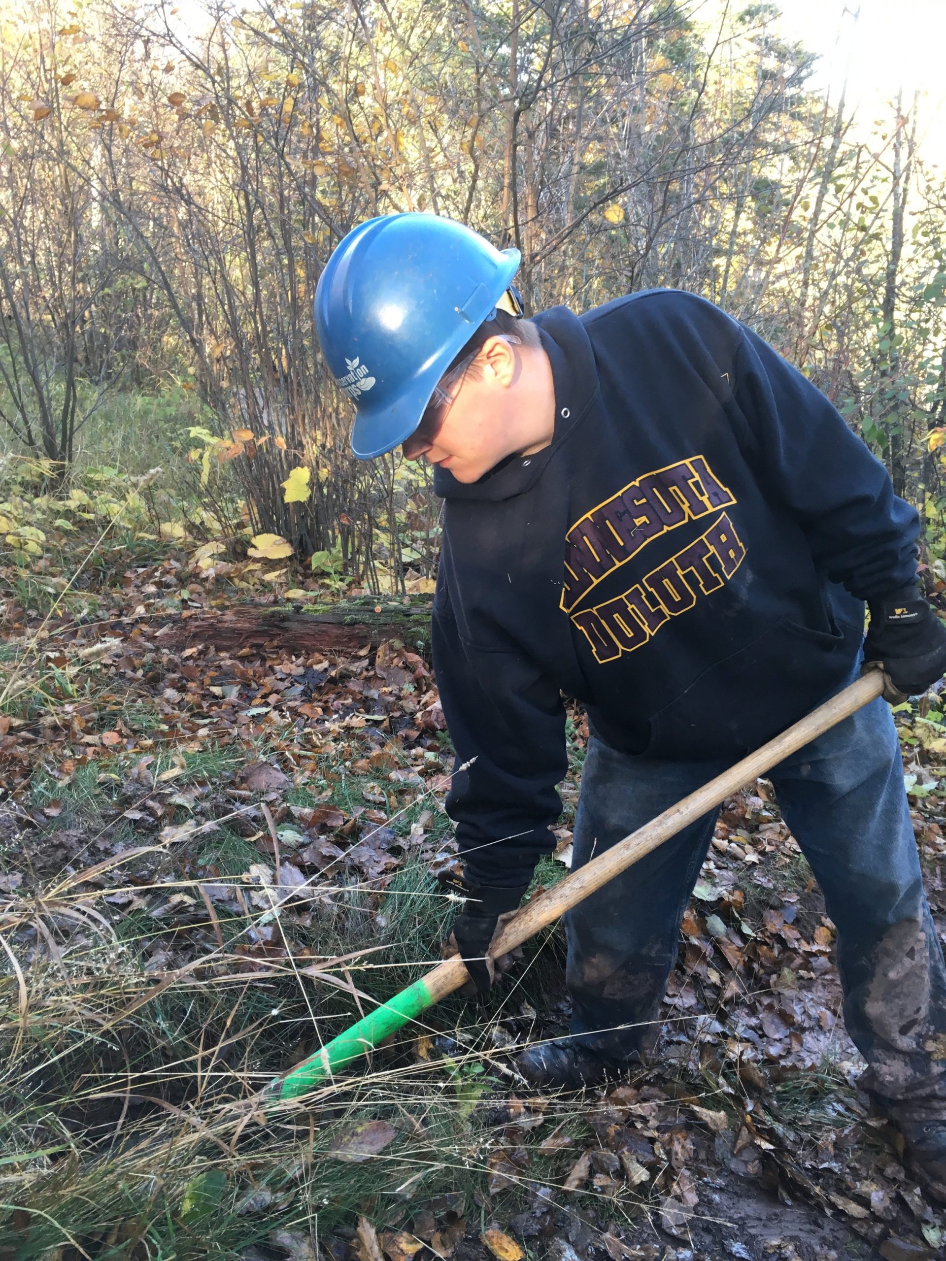 Person in hard haring using shovel