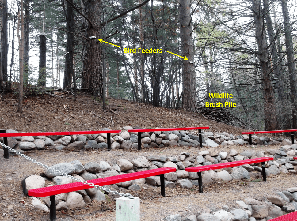 Yellow text pointing to "Bird Feeders" and a "Wildlife Brush Pile" behind red bleechers.