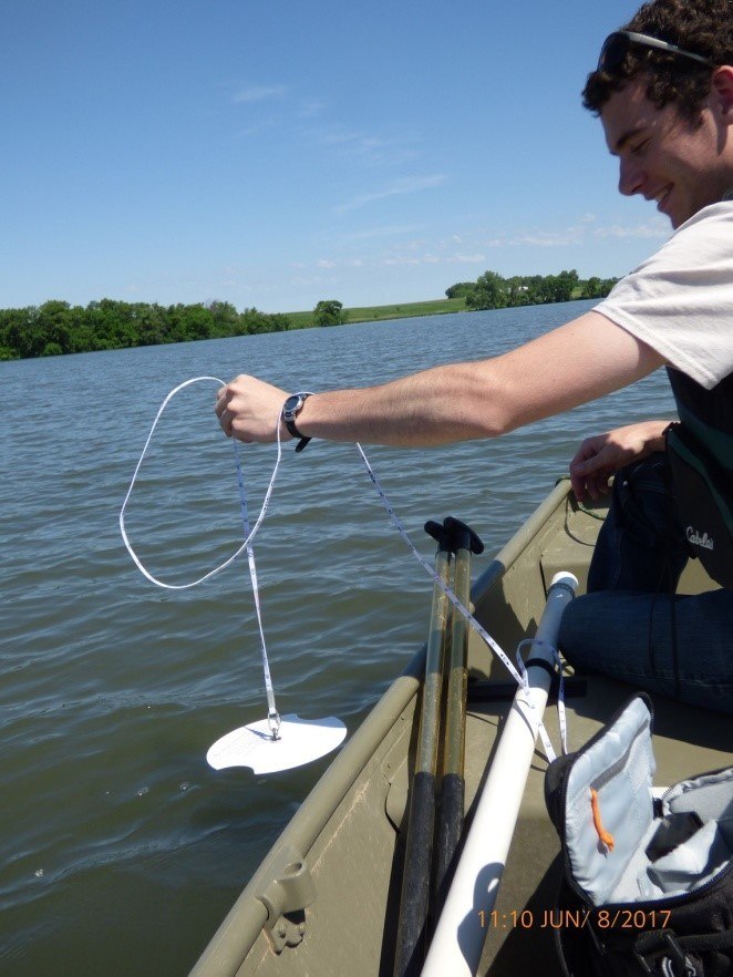 corpmembers testing water clarity from boat