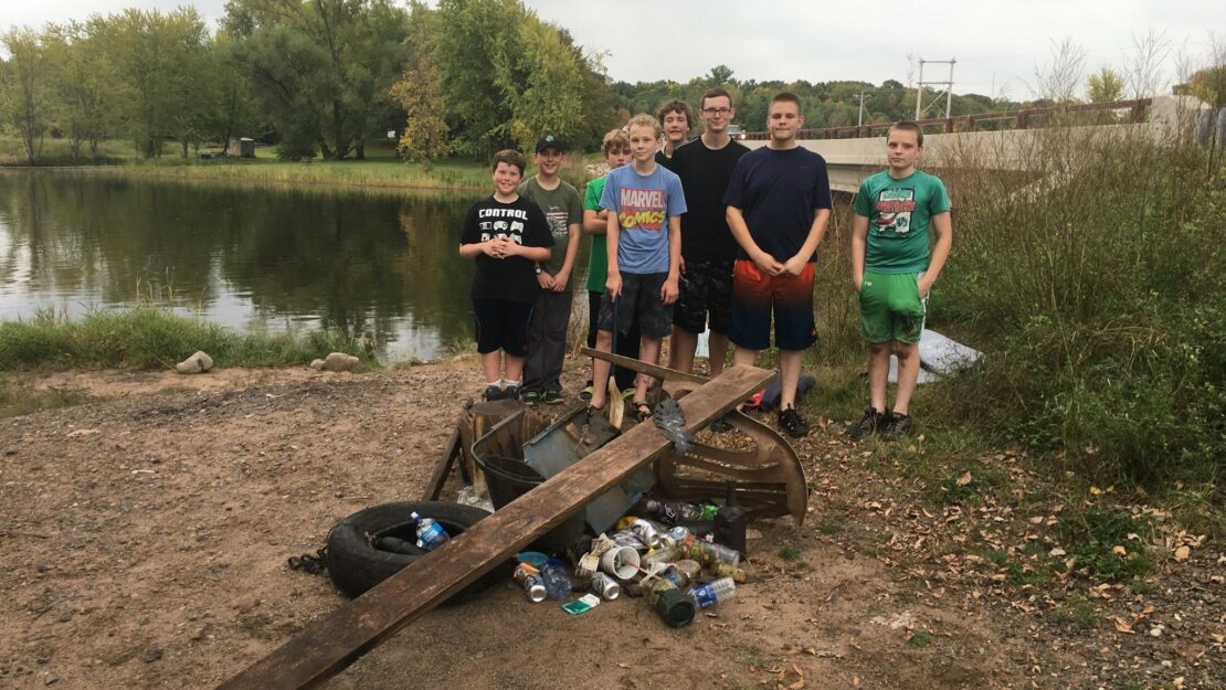 group standing on rivers edge with pile of trash