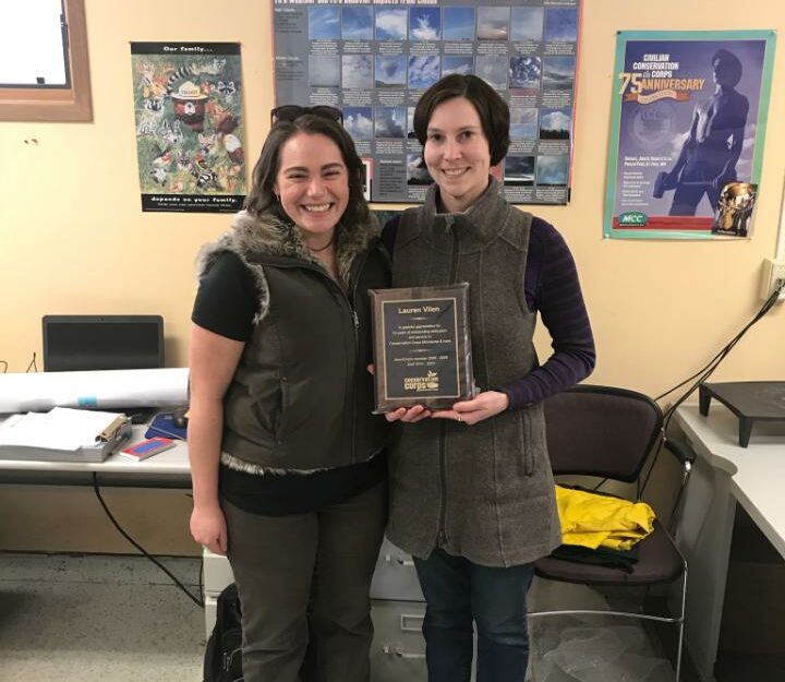 Two people in office with plaque