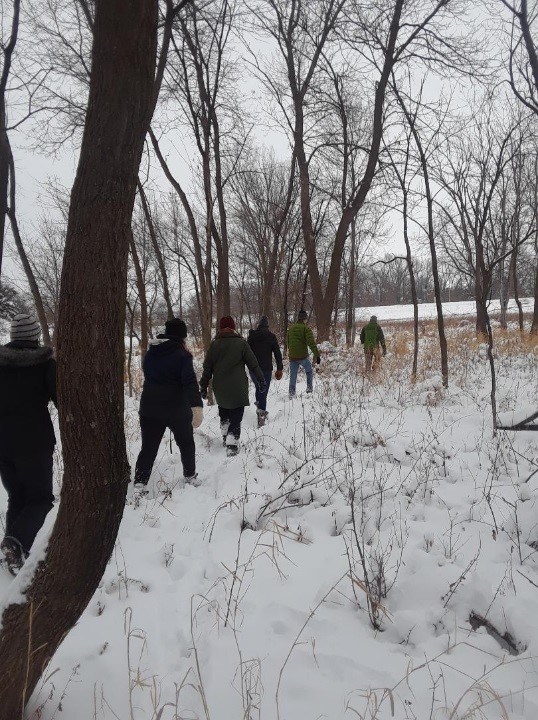 people walking through snowy forest