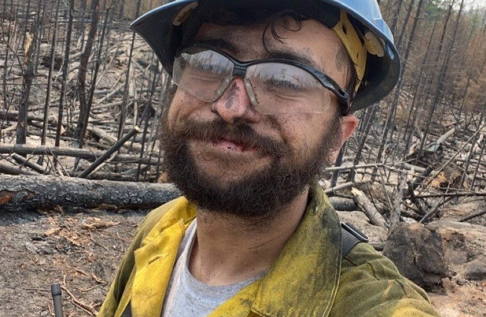 Man in fire fighting gear in a burned forest.