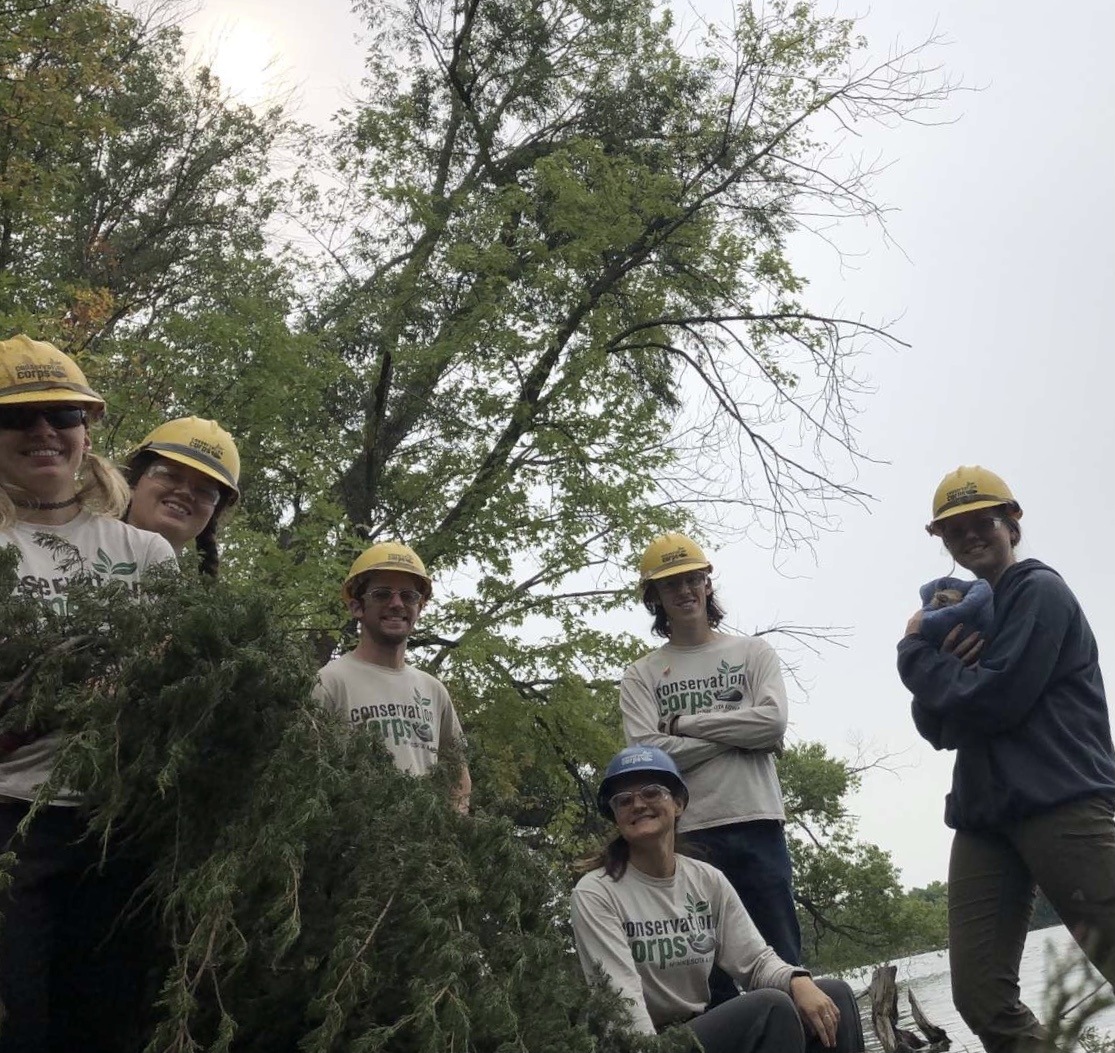 group standing by river holding vegetation 