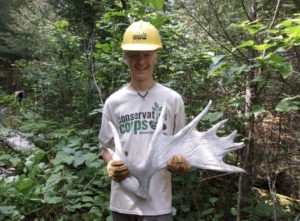 member in Corps shirt holding a moose antler