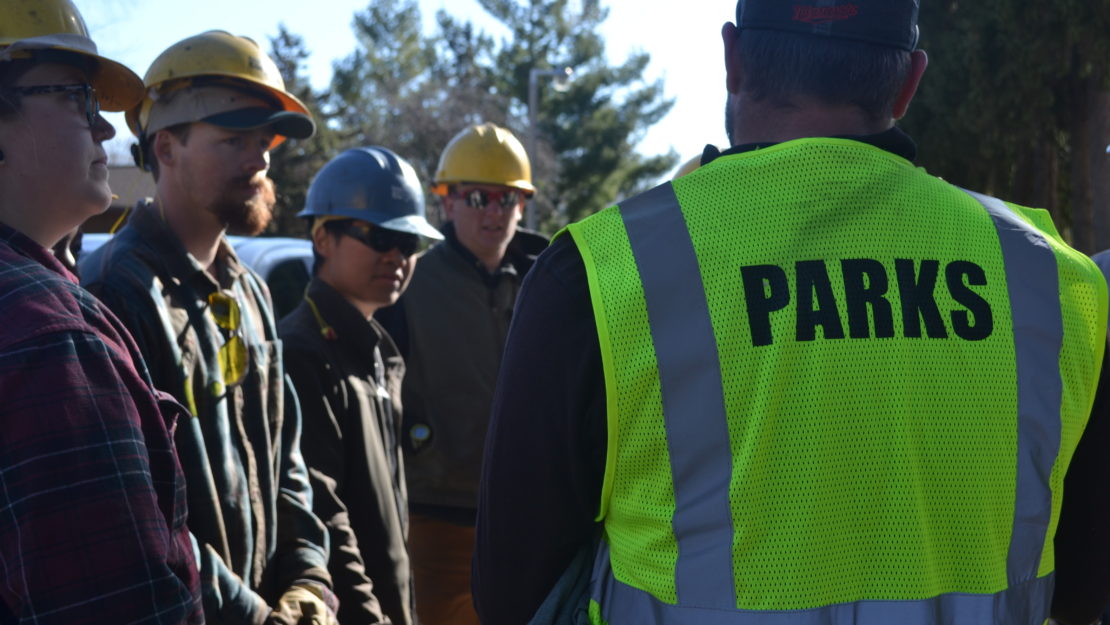 Corpsmembers listening to staff from the City of Rochester during a tree planting event