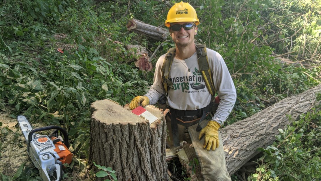 man posing next to downed tree