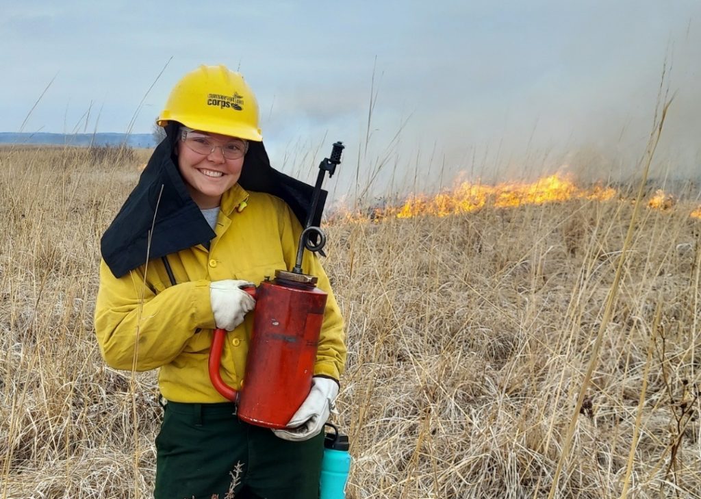 member holding a red can at a prairie on fire.