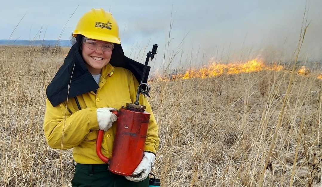 member holding a red can at a prairie on fire.