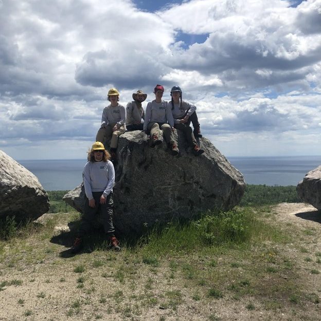 Corpsmembers sitting on big rock on lakeshore