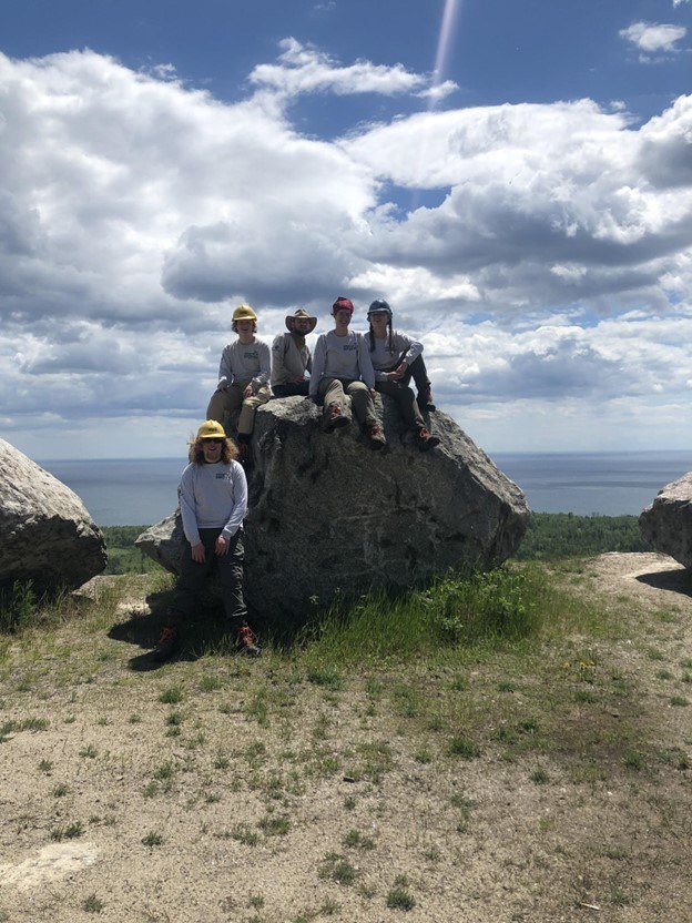 Corpsmembers sitting on big rock on lakeshore