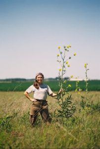 woman next to tall plant in a field