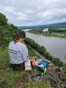 member sitting on overlook of river