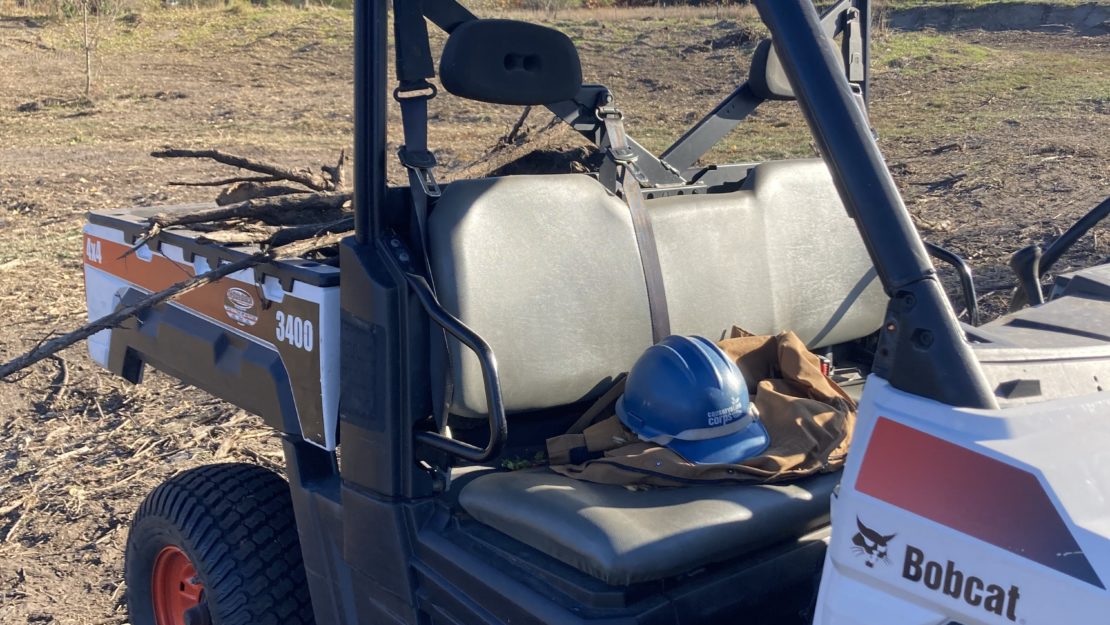 ATV in field with helmet and work gloves on seat