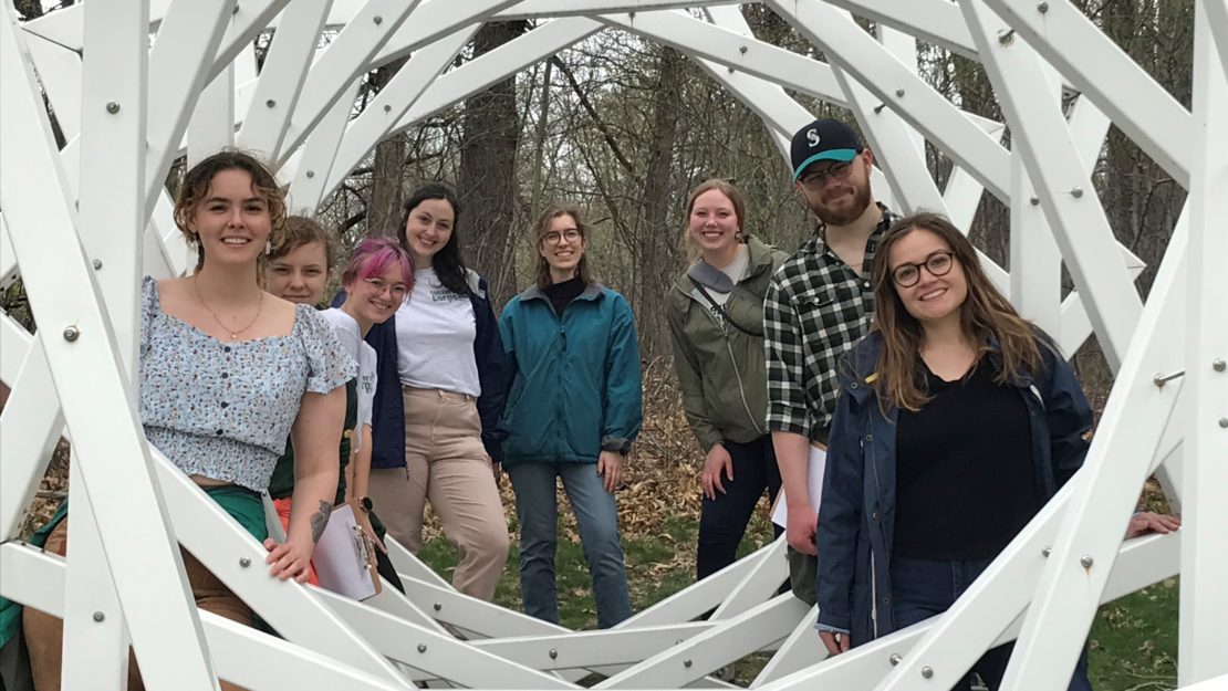 People standing within a geometric sculpture looking at the camera for a group photo