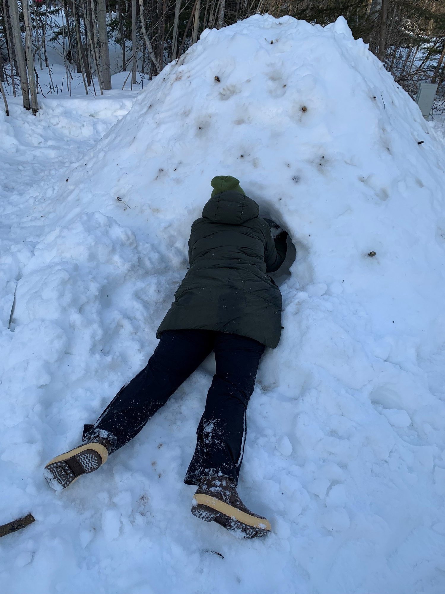 person in winter gear digging into a pile of snow.