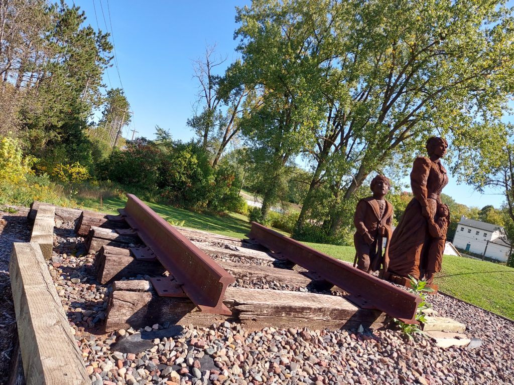 Statues next to a cut out section of a railroad 