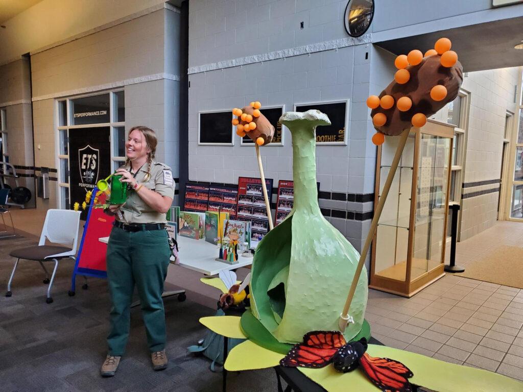 A person in a naturalist uniform gives a presentation with the paper mache prop.