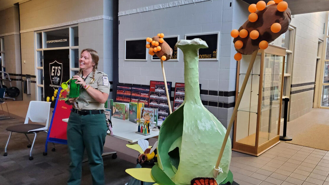 A person in a naturalist uniform gives a presentation with the paper mache prop.