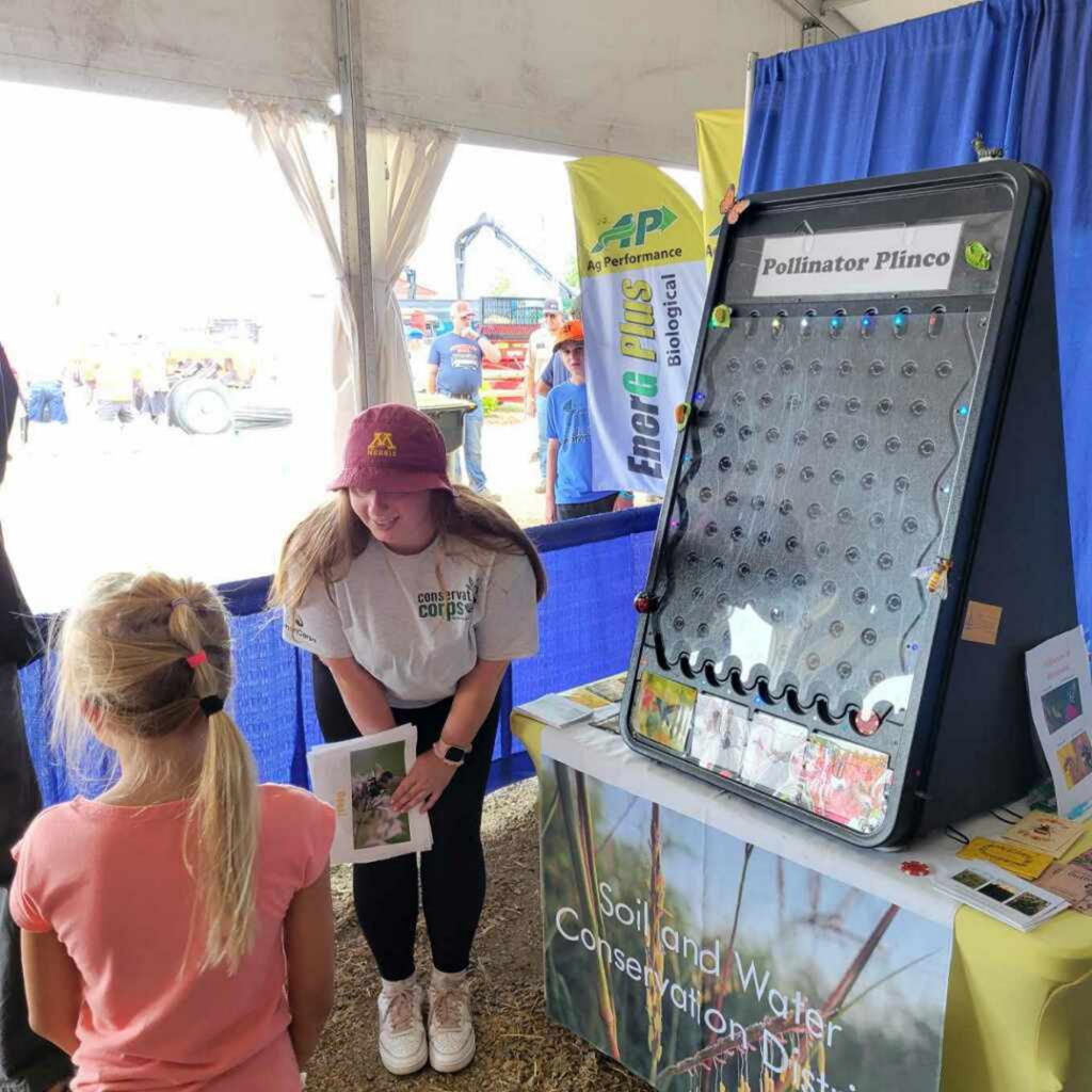 A person crouching to talk with a child at a plinko board.