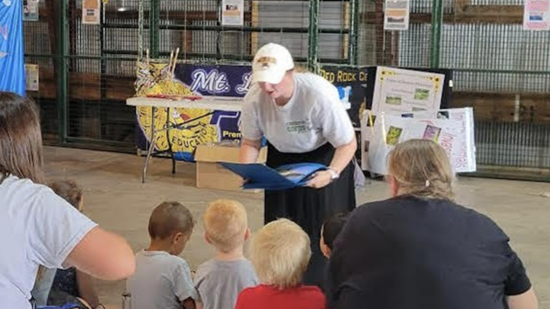 A person speaking to a group of children.