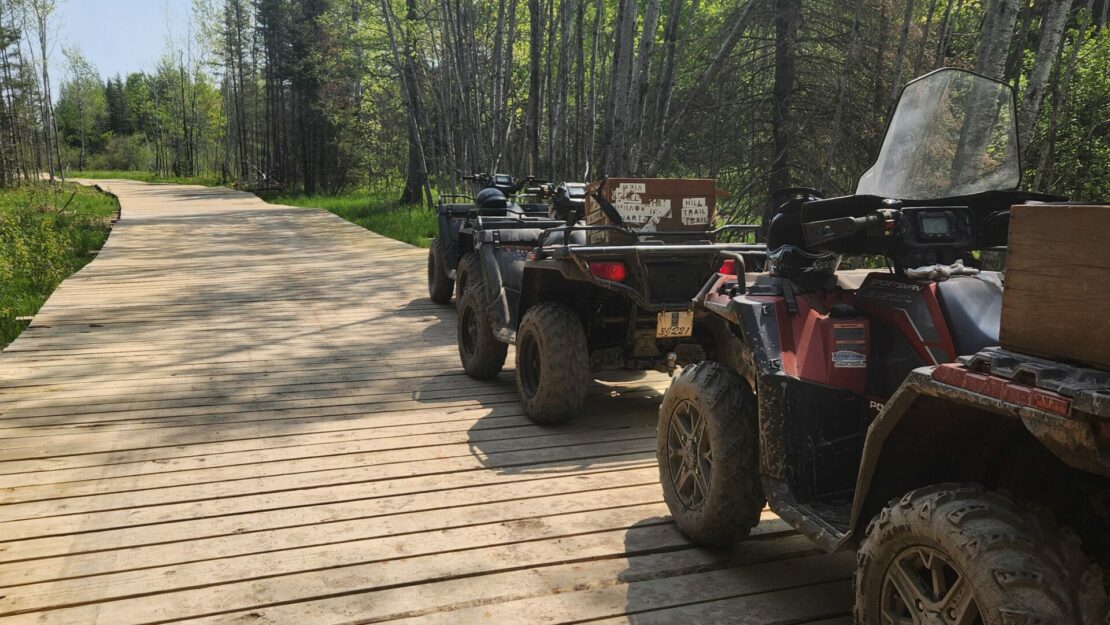 Three ATVs on a boardwalk.