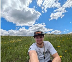 A person in a Corps shirt sitting in a prairie.