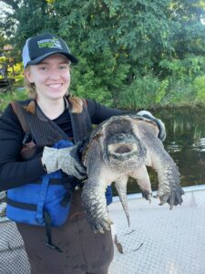 A person holding up a large turtle.