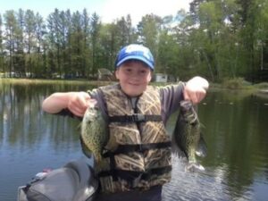 A child holding up two small fish.