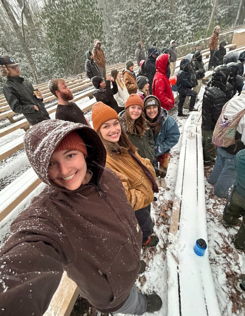 Selfie of several people in standing near in amphitheater benches in snow.