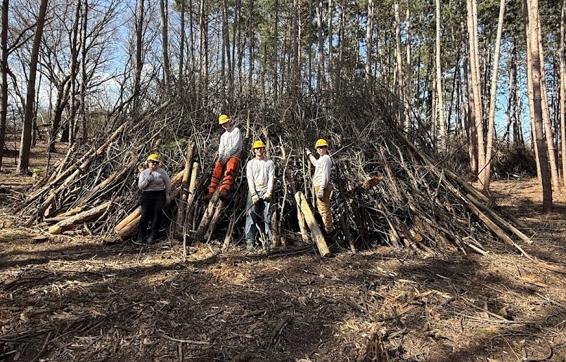 People standing in front of a brush pile