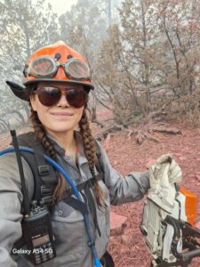 A person in fire gear in a forest,