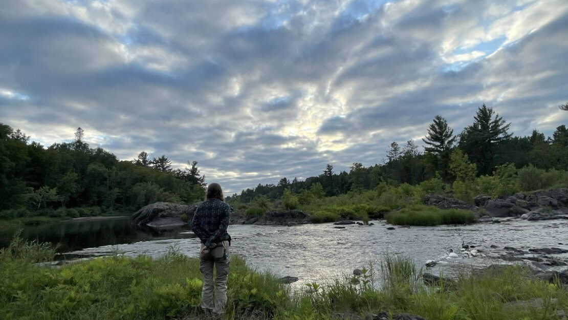 A person standing by the water on a cloudy day.