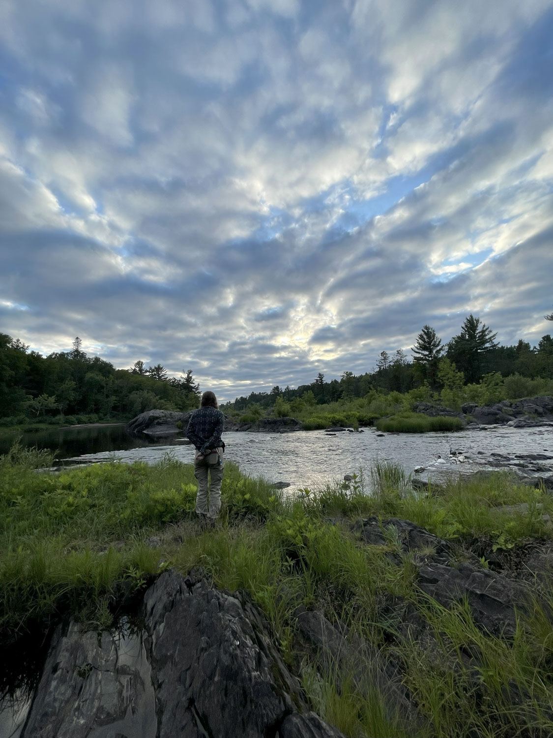 A person standing by the water on a cloudy day.