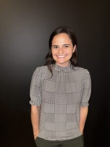 A person smiling at the camera against a black background.