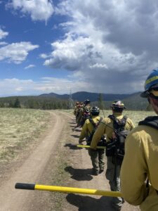 A line of firefighters walking along a dirt road.