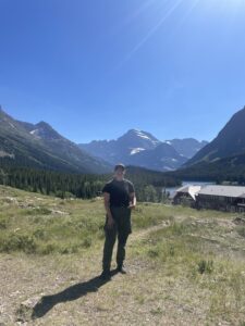 A person standing with mountains in the background.